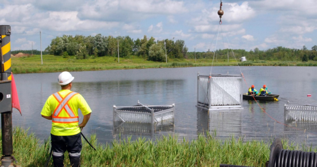 Operators watch as BioCord reactors are lowered into a wastewater lagoon